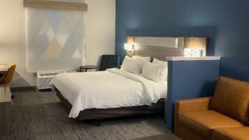 Camera d'albergo moderna con un ampio letto, un divano, un tavolino e una TV a parete.