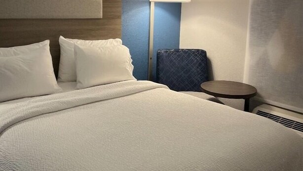 A hotel room with a large bed, a bedside table, a lamp, and a window with curtains. - Holiday Inn Express & Suites Loveland by IHG (Loveland)