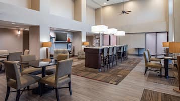 Un vestíbulo de hotel con zona de bar, asientos y televisor.