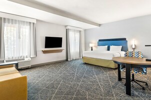 Una habitación de hotel con cama, televisión, escritorio y silla.