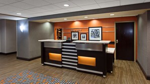 A reception desk with a modern design, featuring a counter, a staircase, and framed pictures on the wall.