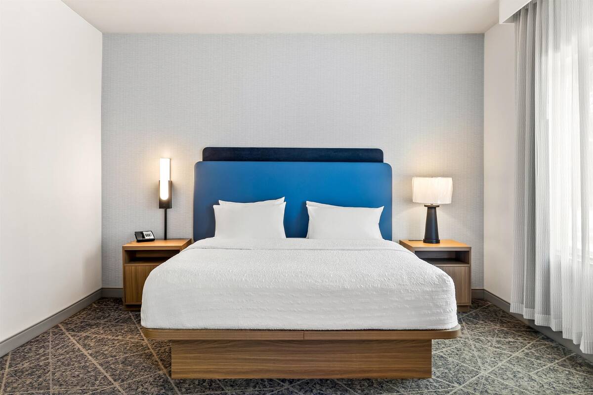 A hotel room with a large bed, two bedside tables, and a nightstand.