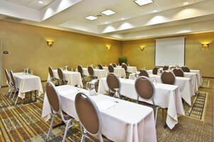 Un salón de conferencias con mesas dispuestas para reuniones, equipado con sillas y jarras de agua.
