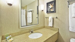 A hotel bathroom with a large mirror, a sink, and a towel rack.