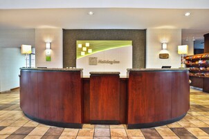 Una mesa de recepción con un letrero de 'Holiday Inn', una placa conmemorativa y una barra de aperitivos al fondo.