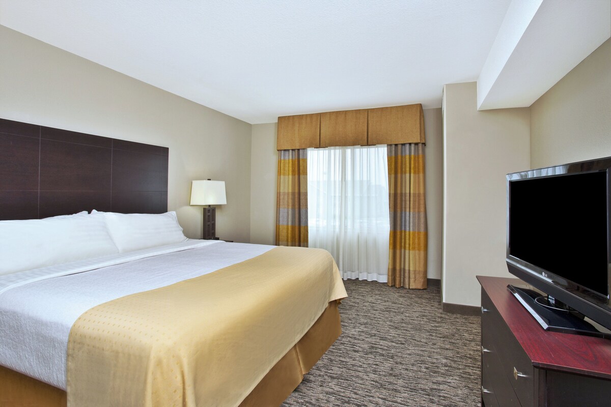 A hotel room with a bed, a television, a nightstand, and curtains.