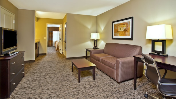 A hotel room with a sofa, a TV, a desk, and a lamp.