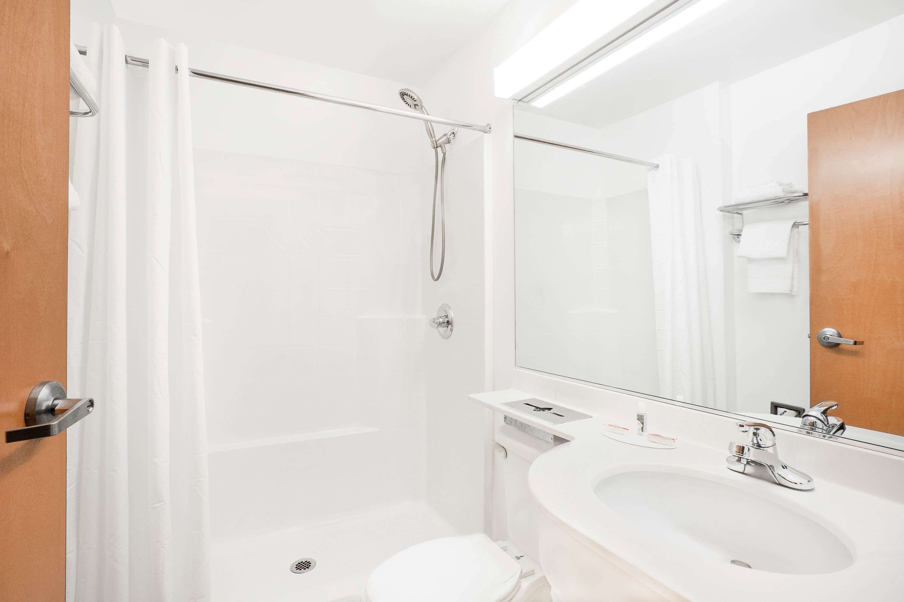 A modern bathroom with a shower, toilet, sink, and a large mirror.