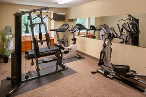 A gym with cardio machines, weight machines, and a mirror.