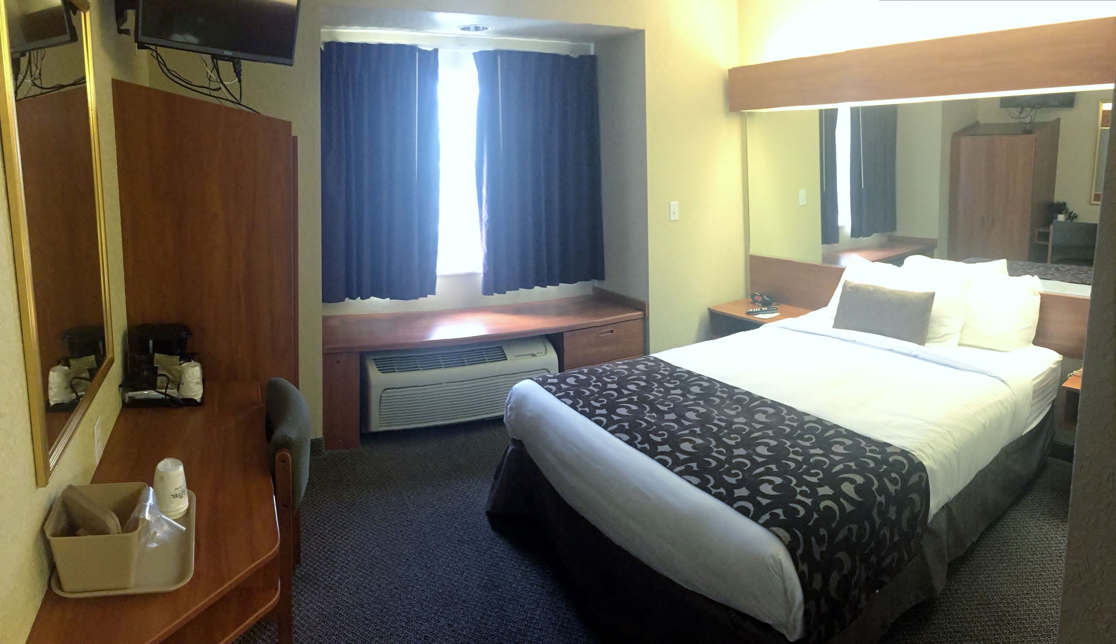Een hotelkamer met een bed, een bureau, een spiegel en een kledingkast.