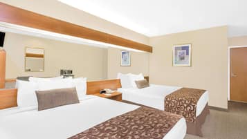 A hotel room with two beds, a large mirror, and a door.
