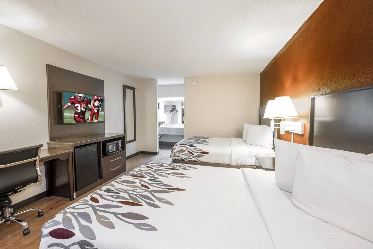 Ein Hotelzimmer mit Bett, Schreibtisch, Fernseher und Lampe.