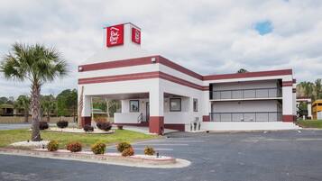 Un hotel Red Roof Inn de dos pisos, con estacionamiento techado y una palmera en primer plano.