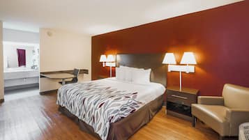 A hotel room with a bed, bedside lamps, a chair, a desk, and a mirror.