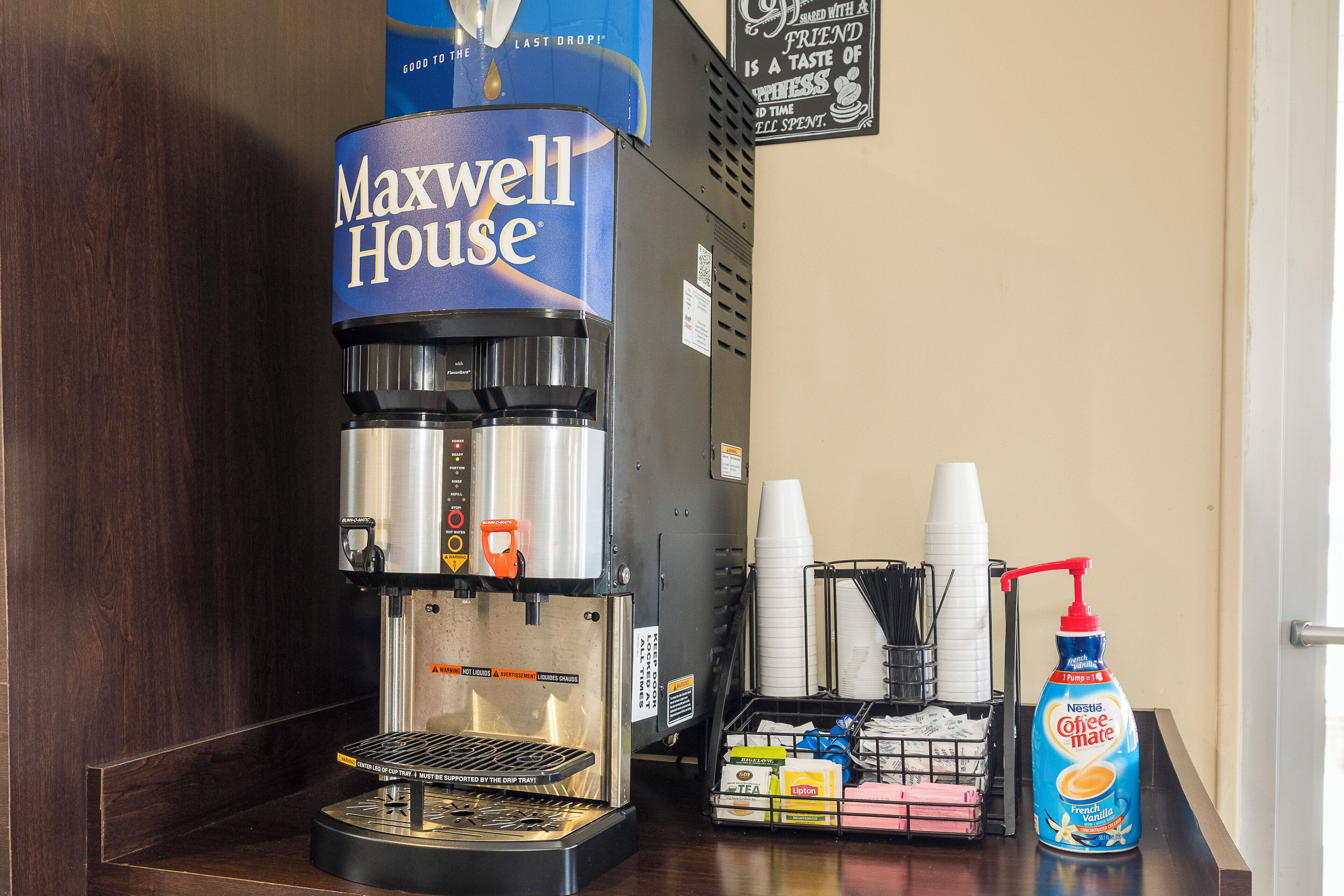 Una cafetera con una cápsula de café 'Maxwell House', un recipiente para goteo y una botella de crema de café 'French Vanilla'.