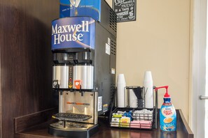 Une machine à café avec une dosette de café « Maxwell House », un bac de récupération et un flacon de crème aromatisée à la vanille française.