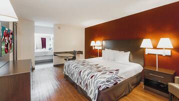 A hotel room with a bed, bedside tables, a desk, and a mirror.