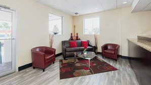 A modern living room with a sofa, two armchairs, a coffee table, and a large window providing a view. - Red Roof Inn Walterboro (Walterboro)