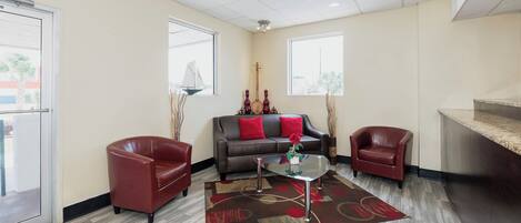 A modern living room with a sofa, two armchairs, a coffee table, and a large window providing a view.