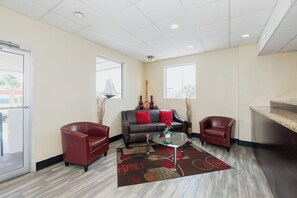 A modern living room with a sofa, two armchairs, a coffee table, and a large window providing a view. - Red Roof Inn Walterboro (Walterboro)
