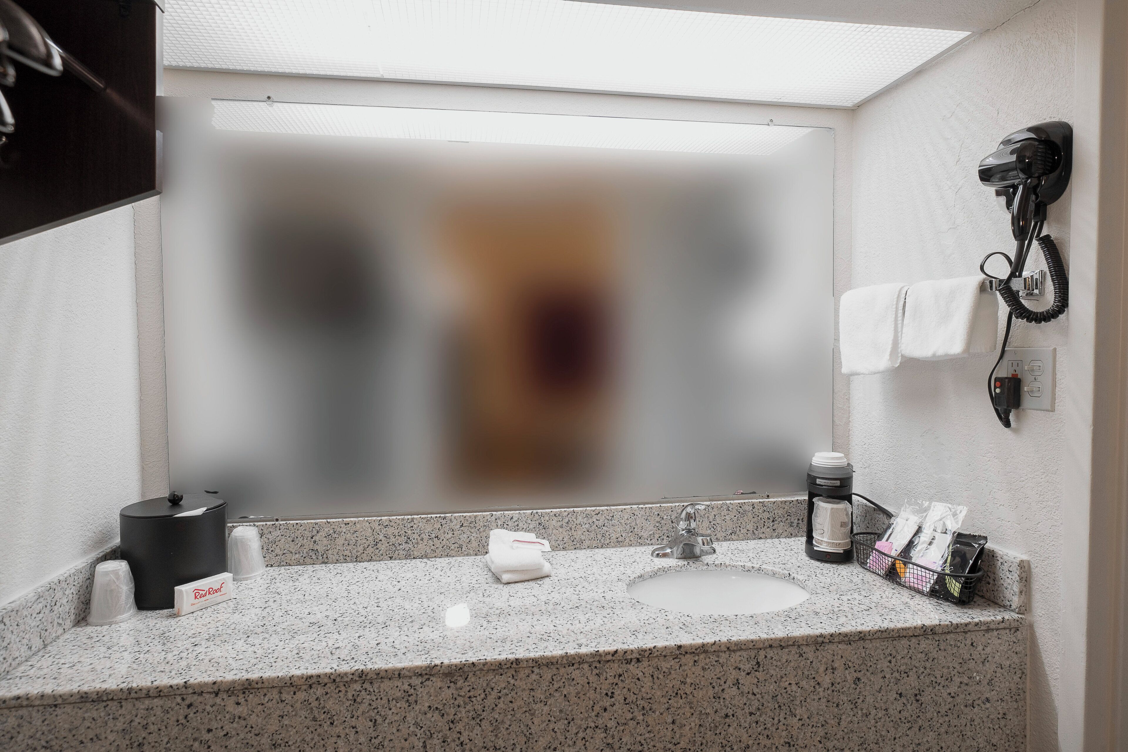 Un baño con encimera de granito, un secador de pelo montado en la pared y un perchero para toallas.