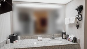 A bathroom with a granite countertop, a hairdryer mounted on the wall, and a towel rack. - Red Roof Inn Walterboro (Walterboro)