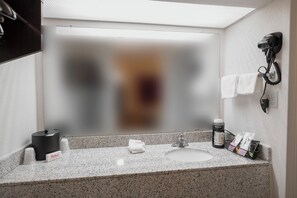 A bathroom with a granite countertop, a hairdryer mounted on the wall, and a towel rack. - Red Roof Inn Walterboro (Walterboro)