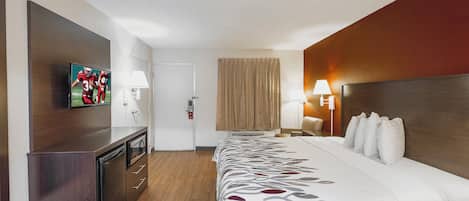 Una habitación de hotel con cama, televisión, escritorio y puerta.