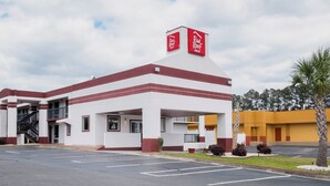 A Red Roof Inn with a two-story structure, a covered parking area, and a palm tree in the foreground. - Red Roof Inn Walterboro (Walterboro)