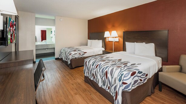 A hotel room with two beds, a desk, a chair, and a TV. - Red Roof Inn Walterboro (Walterboro)