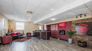 A hotel lobby with a reception desk, seating area, and a Red Roof Inn sign. - Red Roof Inn Walterboro (Walterboro)