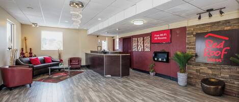 Un vestíbulo de hotel con mostrador de recepción, zona de estar y un cartel de Red Roof Inn.