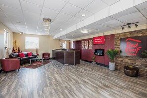 A hotel lobby with a reception desk, seating area, and a Red Roof Inn sign. - Red Roof Inn Walterboro (Walterboro)