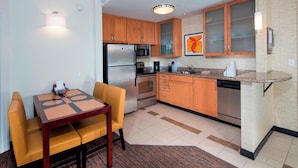 A compact kitchen with wooden cabinets, a built-in microwave, a refrigerator, and a coffee maker. - Residence Inn Marriott Dover (Dover)