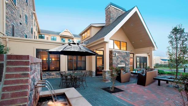 A patio area with outdoor seating, a fire feature, and a stone wall. - Residence Inn Marriott Dover (Dover)