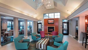 A spacious lobby with teal armchairs, a striped ottoman, and a fireplace. - Residence Inn Marriott Dover (Dover)