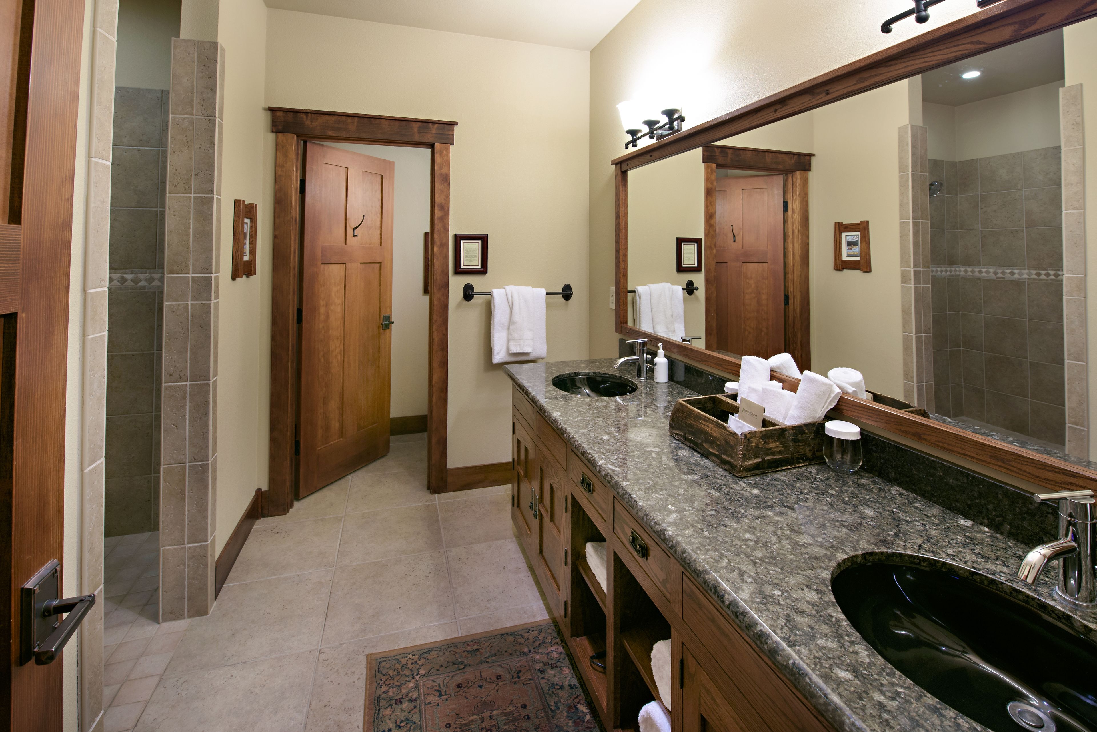 A bathroom with a large mirror, a sink, and a shower area.