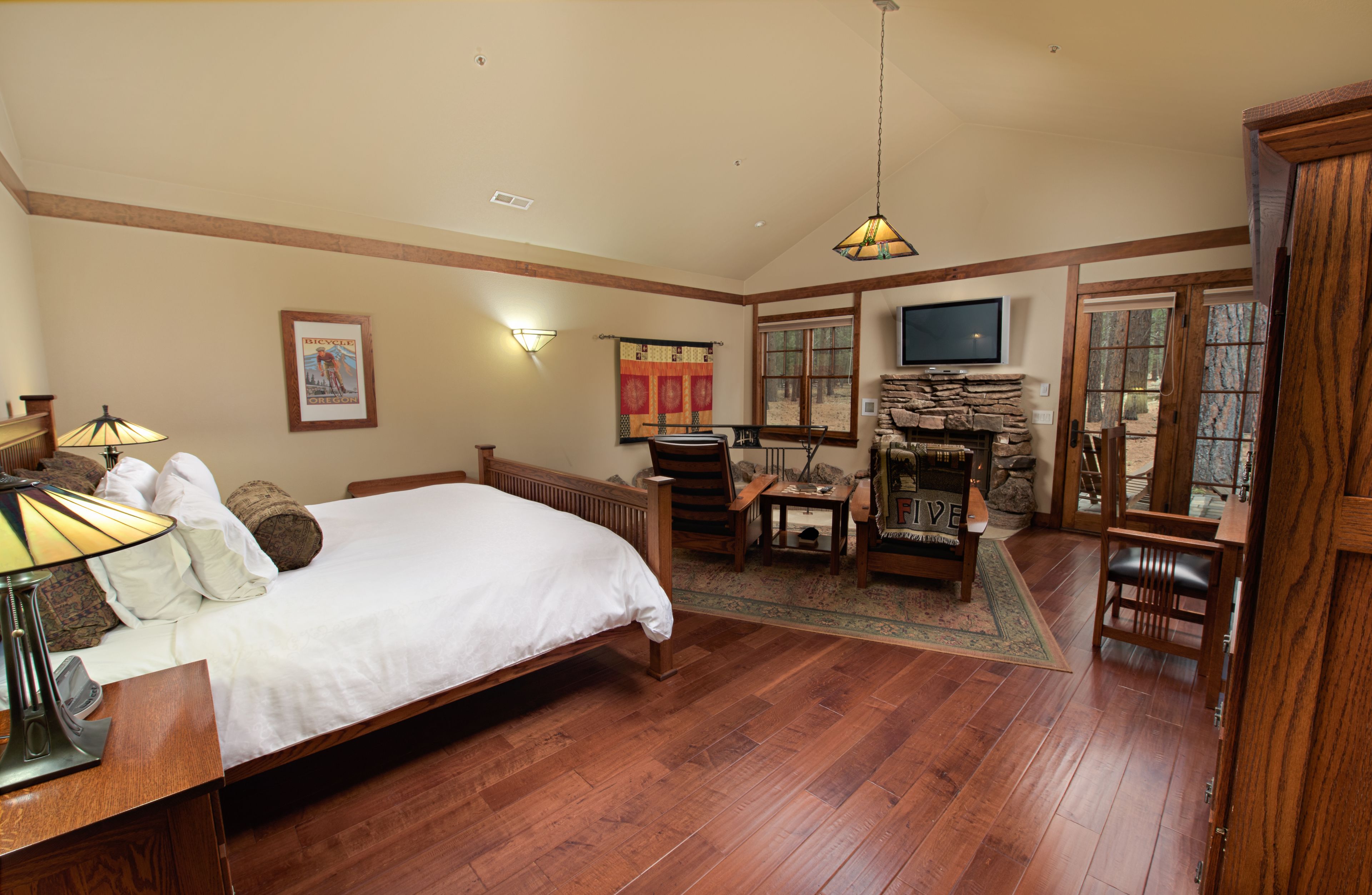 A spacious bedroom with a large bed, wooden furniture, a fireplace, and a television.