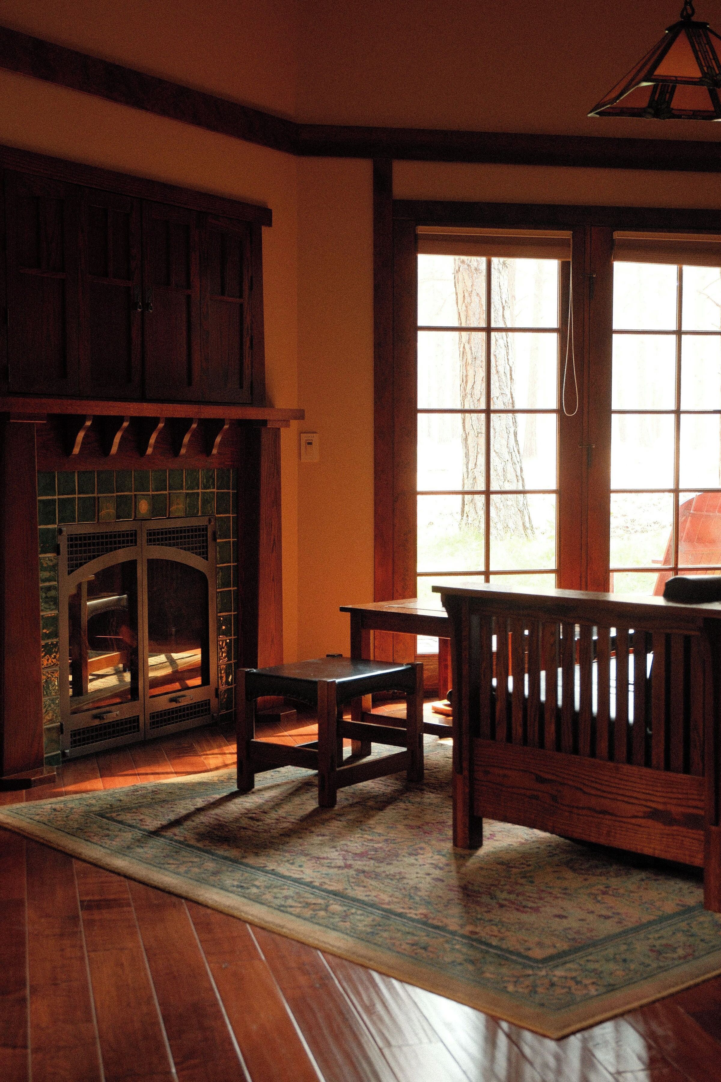 Una habitación con suelo de madera, chimenea, una mesa y un banco.
