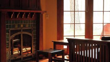 Una habitación con suelo de madera, chimenea, una mesa y un banco.