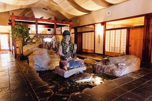 A traditional Japanese interior with tatami flooring, a rock garden, and a statue.