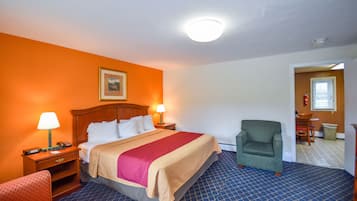 A hotel room with a bed, two bedside lamps, a chair, and a picture on the wall.