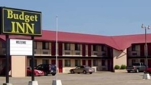 A Budget Inn with a red roof, a 'Welcome' sign, and a parking lot with several cars. - Budget Inn Gadsden (Gadsden)