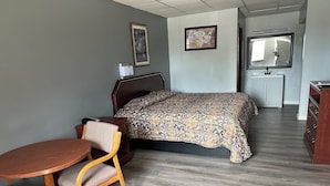 A hotel room with a bed, a desk, a chair, a small table, and a cabinet. - Budget Inn Gadsden (Gadsden)