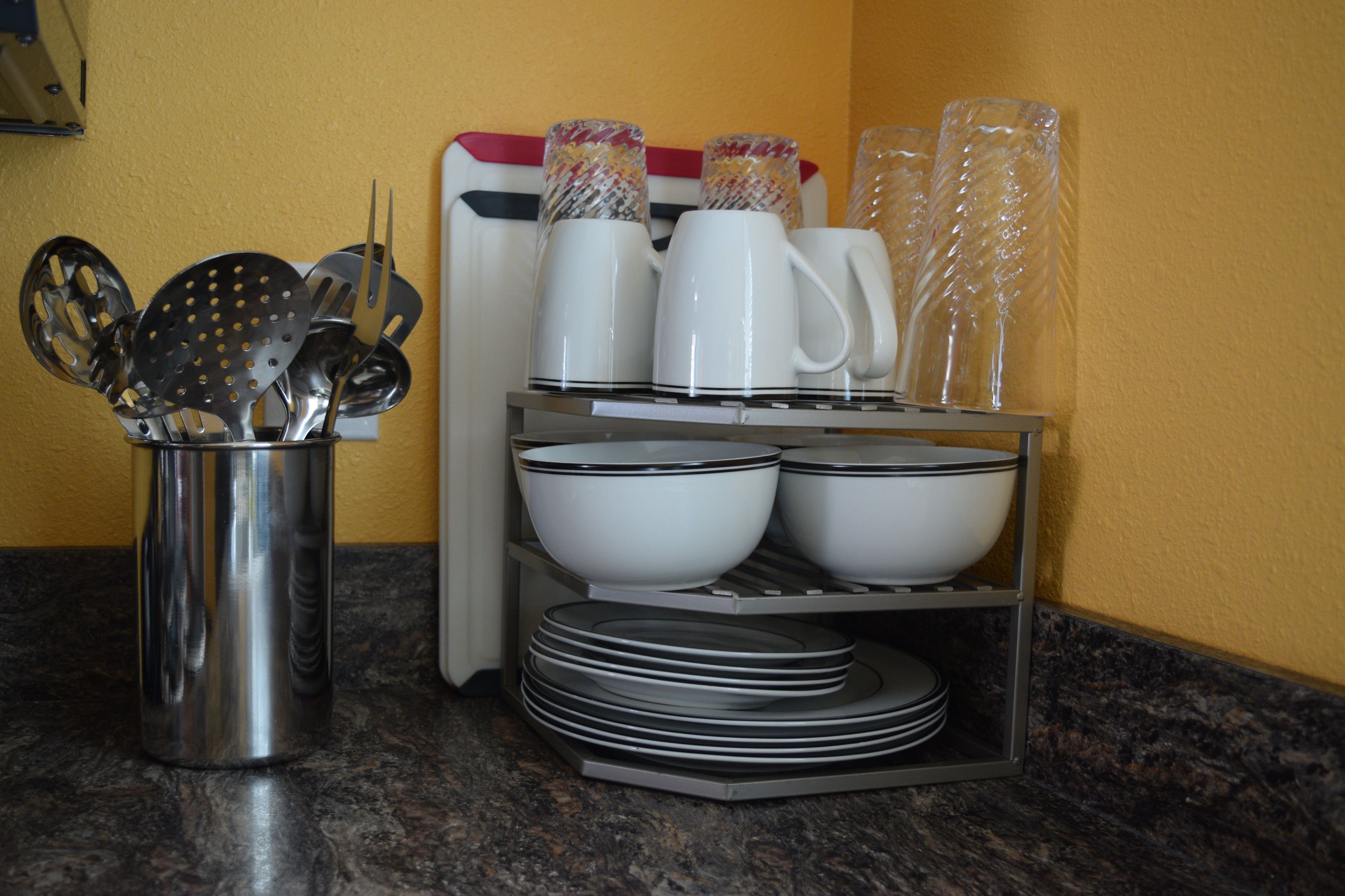 Una encimera de cocina con un portalapices, una cafetera y platos apilados.