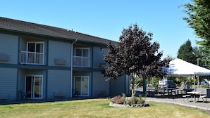 A two-story building with a flat roof, a covered outdoor seating area, and a small tree in the front yard. - The Dew Drop Inn Motel (Forks)