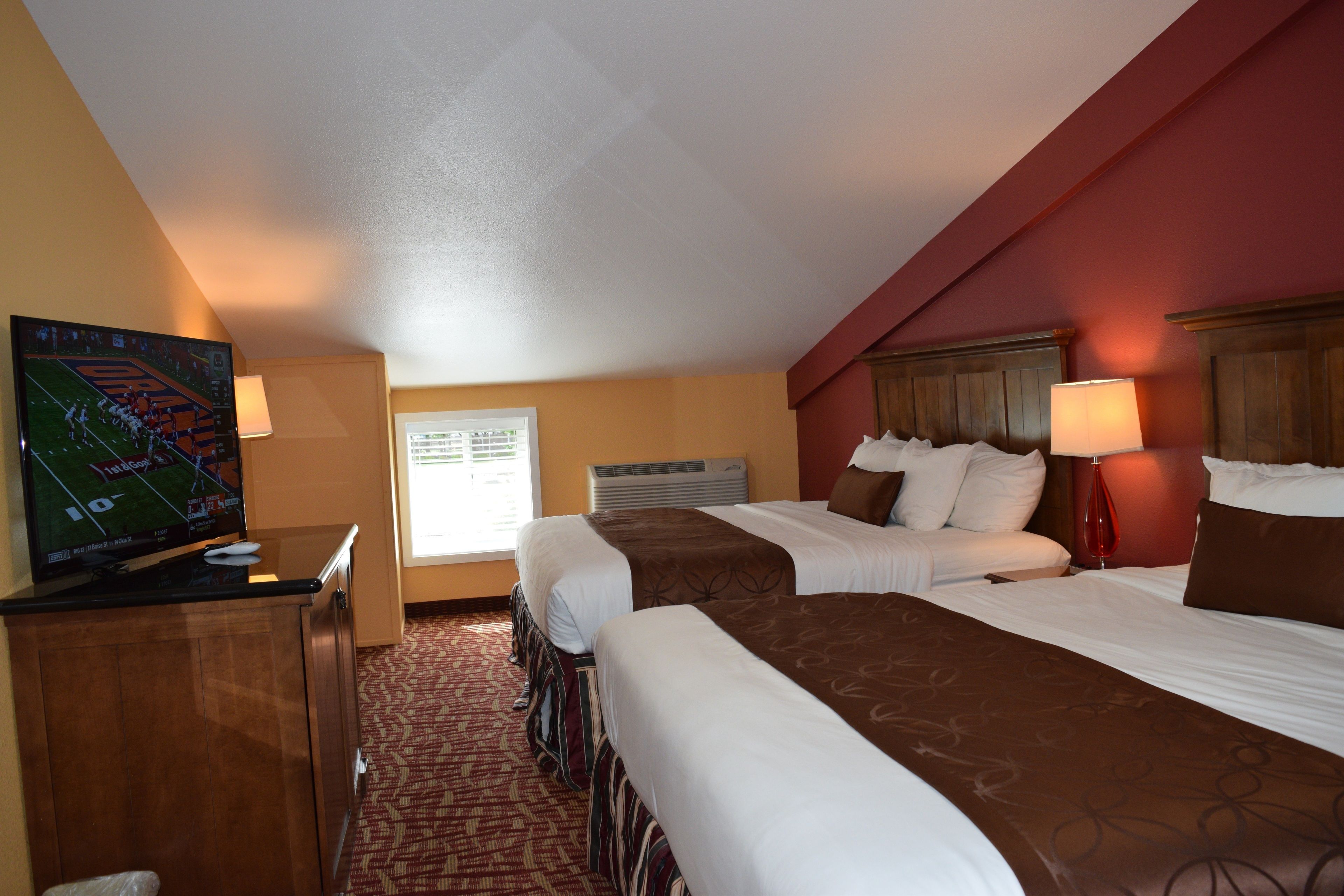 Une chambre d’hôtel avec deux lits, une télévision, un bureau et une fenêtre donnant sur l’extérieur.