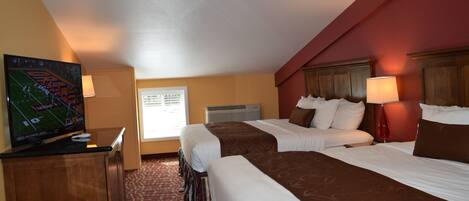 Une chambre d’hôtel avec deux lits, une télévision, un bureau et une fenêtre donnant sur l’extérieur.