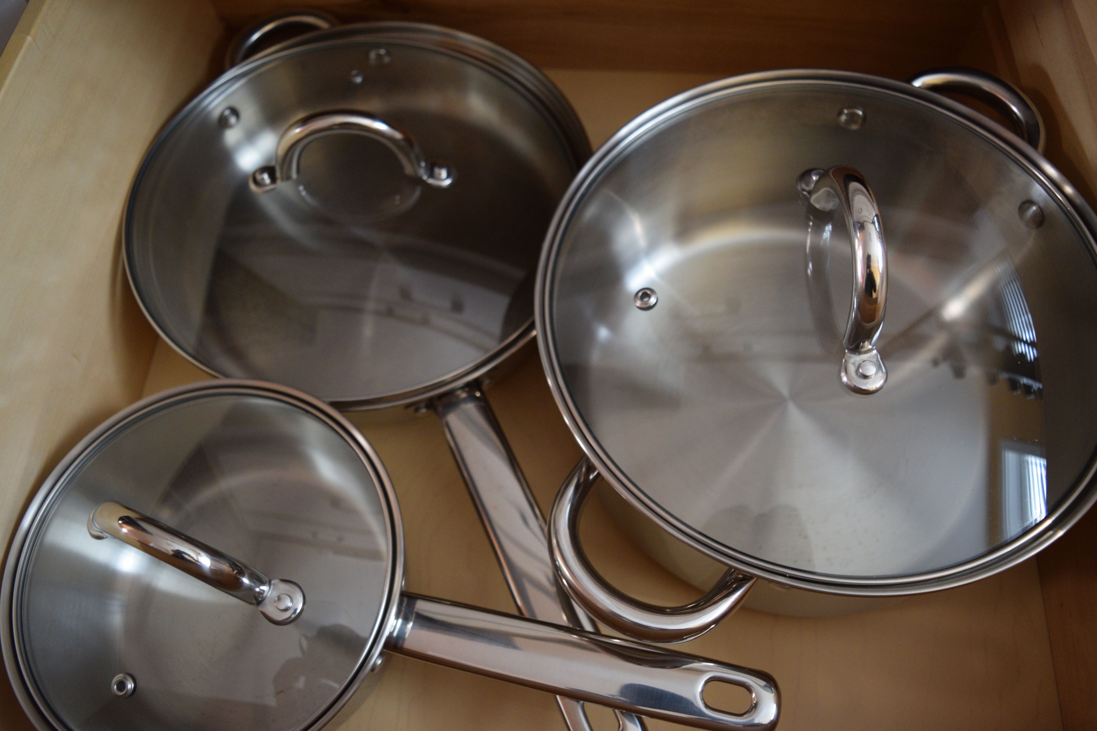 Un tiroir contenant trois casseroles en acier inoxydable, avec leurs couvercles.