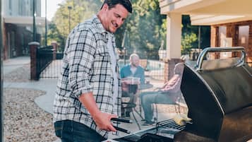 Un hombre asando al aire libre con una barbacoa en primer plano.